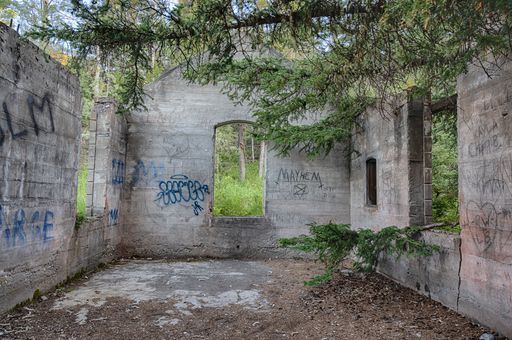 A view of abandoned stone ruins of a building surrounded by green trees