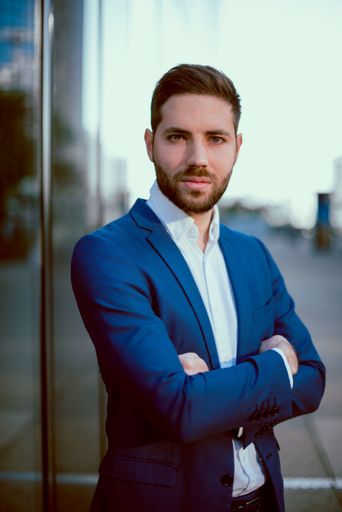 A closeup shot of a young businessman in a blue suit standing outside
