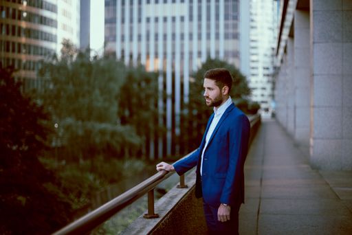 A thoughtful young businessman in a blue suit standing outside