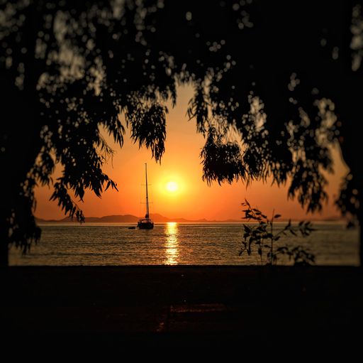 A calm and scenic sunset over the sea in Plataria, Greece, with a ship sailing on the water surface