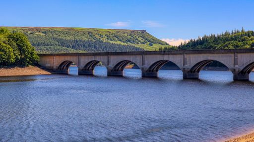 The river running through the arches of the Ashopton bridge under the blue sky