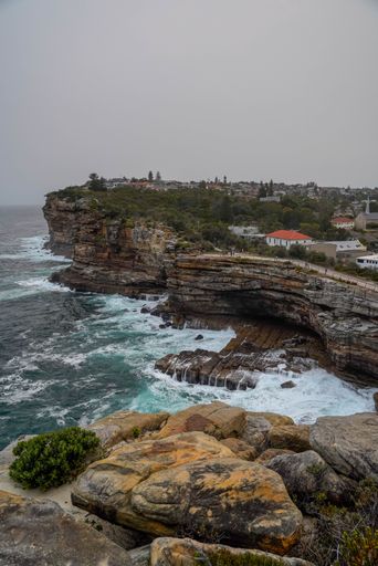 An aerial view of sea waves breaking cliffs in Sydney