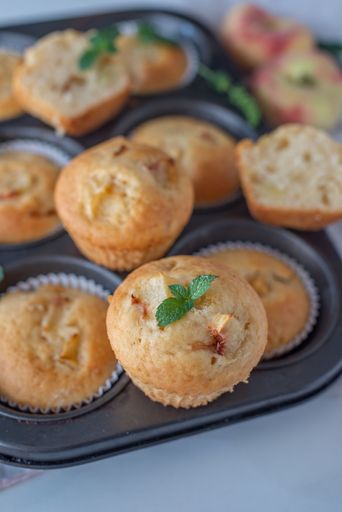 A vertical selective focus shot of homemade vanilla peach muffins on oven tray