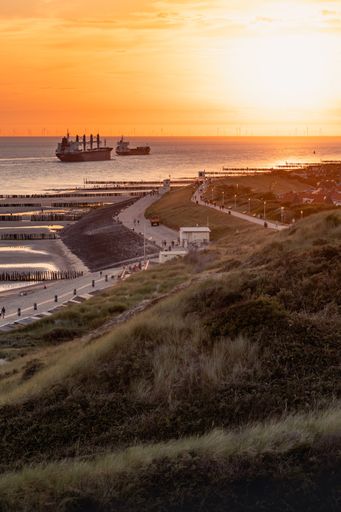 A vertical shot of ships sailing on the sea during sunset in Zoutland, The Netherlands