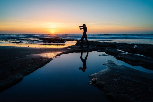 A mesmerizing view of a person at the beautiful Wai-iti Beach during a scenic sunset in New Zealand