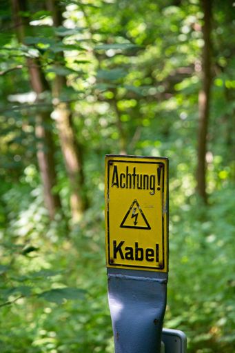 A vertical shot of a German yellow sing - danger cable