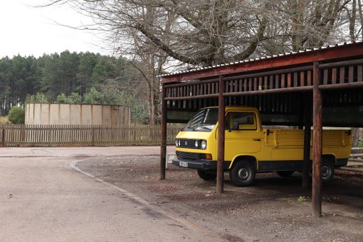 An old yellow Volkswagen (VW) delivery car parked in a garage.