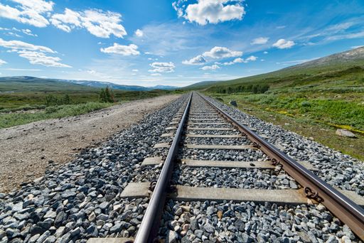 A beautiful shot of train rails moving forward to the hills under the bright calm sky
