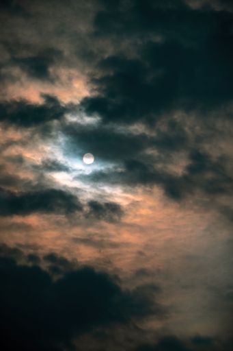 A vertical shot of the Moon against a dramatic cloudy sky at night perfect for wallpapers