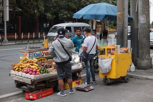 The street vendor sells fruits and ice cream on the side of the road. Makati, Philippines.