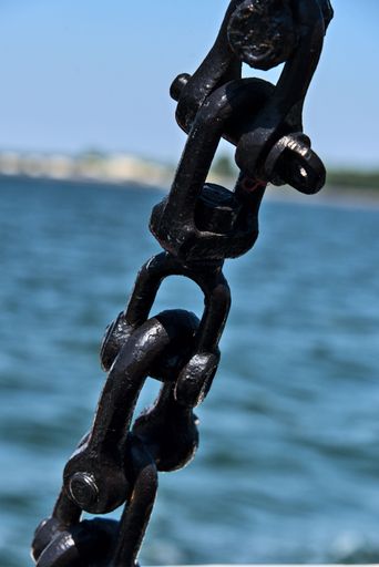 A vertical closeup shot of details on a thick metal boat chain