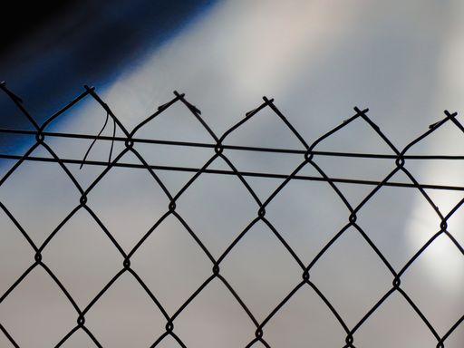 A soft focus of an iron mesh fence with a blurry background