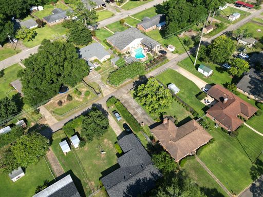 An aerial view of urban residential area with green trees, roads and buildings during the daytime
