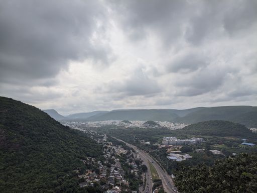 An aerial view of a road in a green mountainous area on a cloudy day