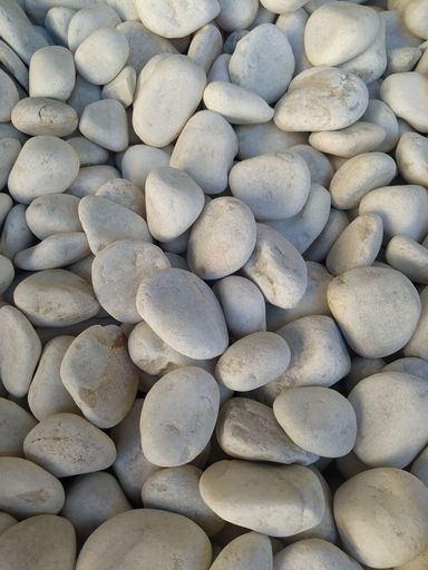 A vertical top view of a collection of white rocks placed on some surface