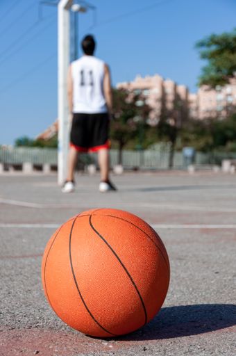 A vertical selective focus shot of a basketball ball in a court and a person in the background