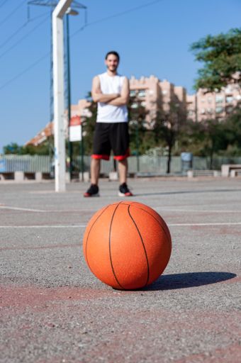 A vertical selective focus shot of a basketball ball in a court and a person in the background