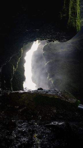 A vertical shot of rocks and moss inside a dark cave