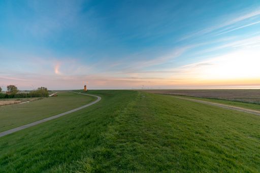 A vibrantly green lawn with Pilsum lighthouse in the distance