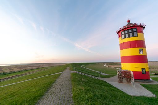 A beautiful shot of a Pilsum lighthouse with a colorful cloudy sky behind