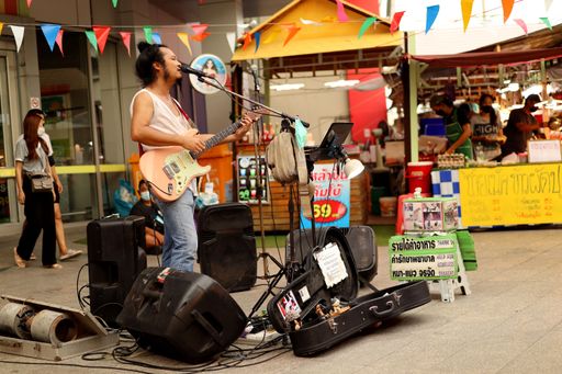 A male street musician playing an electric guitar and singing in Bangkok, Thailand