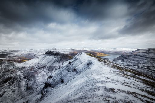 A landscape of Faroe Islands of white ice rocky Mountains View to Vzgar Island under dramatic sky