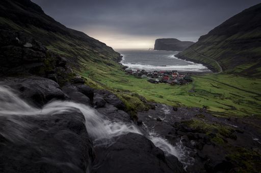 A landscape of Waterfall and the village of tjornuvik in the faroe islands with gray sunset