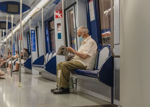 Elderly reading the news in the train.