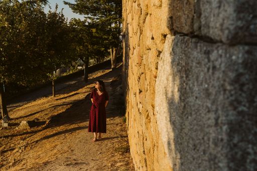 A young caucasian lady walking near the wall of the Castle of Longroiva, Portugal at sunset