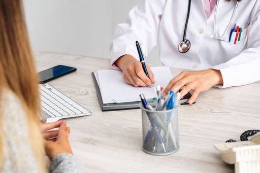 A female doctor in consultation with a patient taking notes