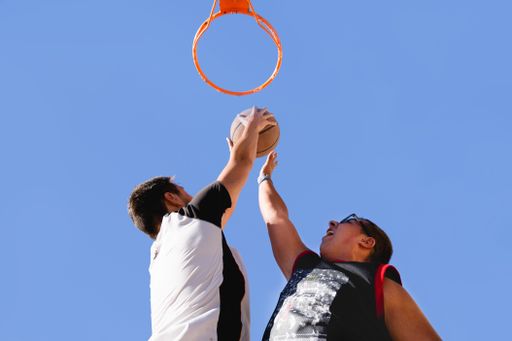 A low angle shot of two basketball players playing with the clear blue sky in the background