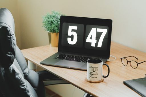 A working laptop and cup of coffee on a wooden desk in the office