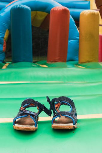 A vertical shot of kids sandals left in front of the inflatable trampoline