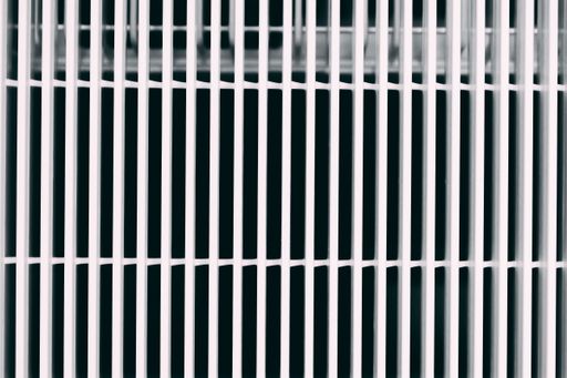A closeup view of metal white bars on the windows of the building