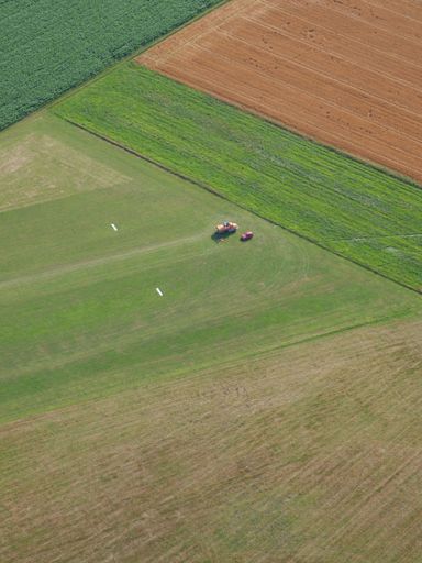 A bird's eye view of a tractor working in green agricultural field