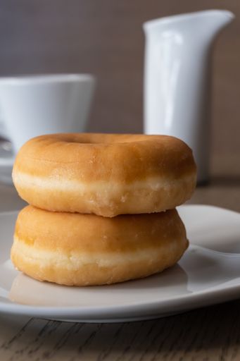 A vertical closeup shot of two fresh donuts on a plate
