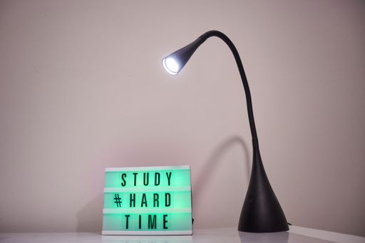 A lamp and a desk with text study hard time on a table in the room
