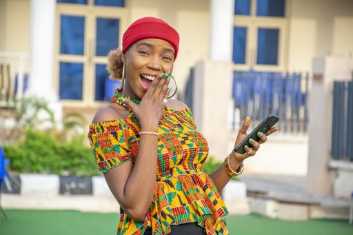 A pretty young African woman smiling and using her mobile phone outdoors
