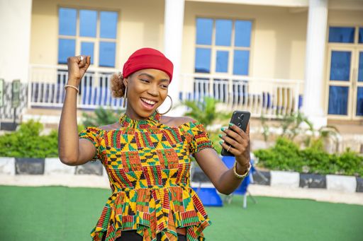 A pretty young African woman smiling and using her mobile phone outdoors