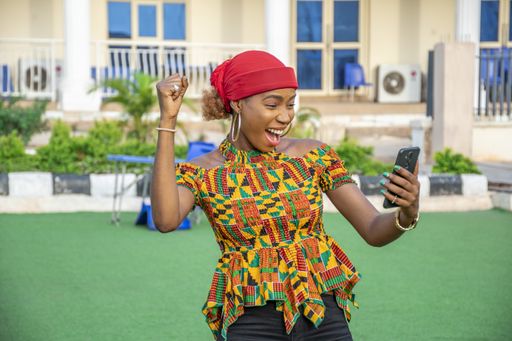 A pretty young African woman smiling and using her mobile phone outdoors