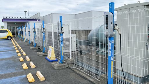 A row of NEC Corp. standard electric vehicle chargers atop a rooftop parking lot at an AEON Mall with a single car charging at one of the stans