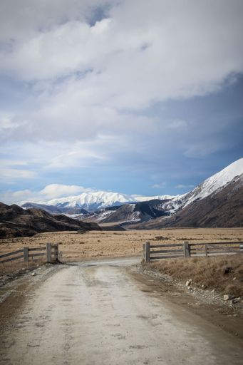 A vertical shot of a road on the background of snowy mountains