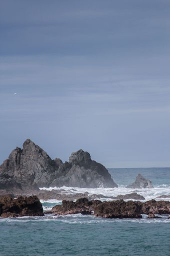 A vertical shot of crashing waves into cliffs