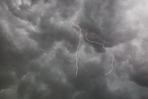 A beautiful shot of lightning striking in a stormy gray sky with rainfall