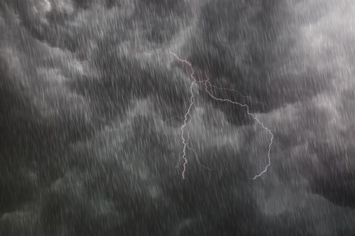 A beautiful shot of lightning striking in a stormy gray sky with rainfall