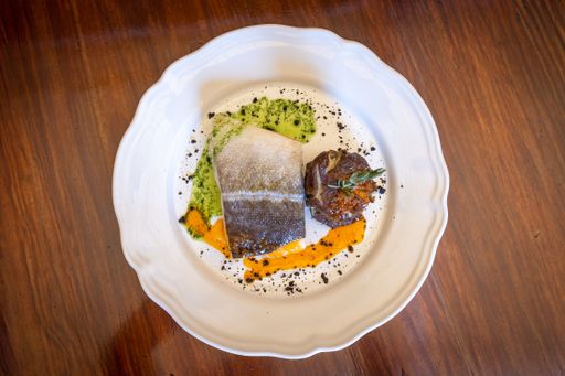A top view a white plate with served fish and potatoes