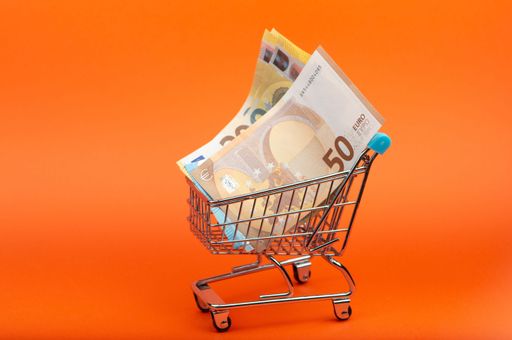 Euro banknotes of different nominals in the shopping cart on bright orange background