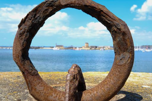 A closeup shot of a huge anchor chain on the beach with the sea in the background