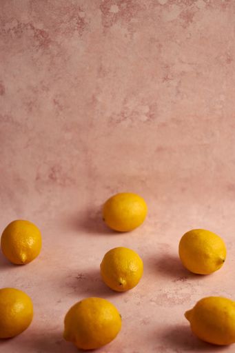 A vertical shot of lemons on a pink marble background