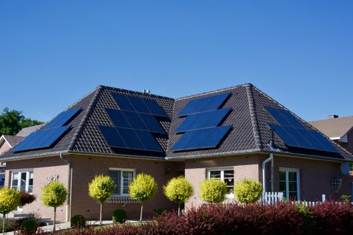 A house with solar panels covering its tiled roof under a clear blue sky on a sunny day
